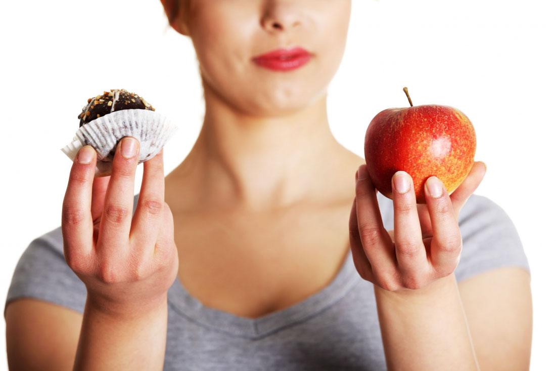 Žena srovnává muffin a jablko