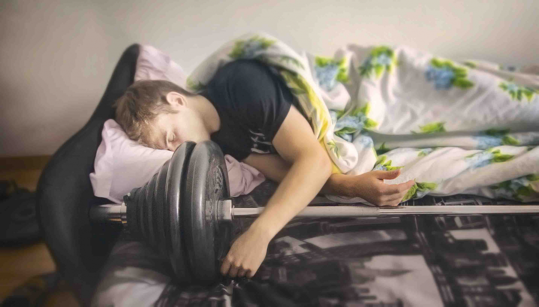Muž spí vedle činky